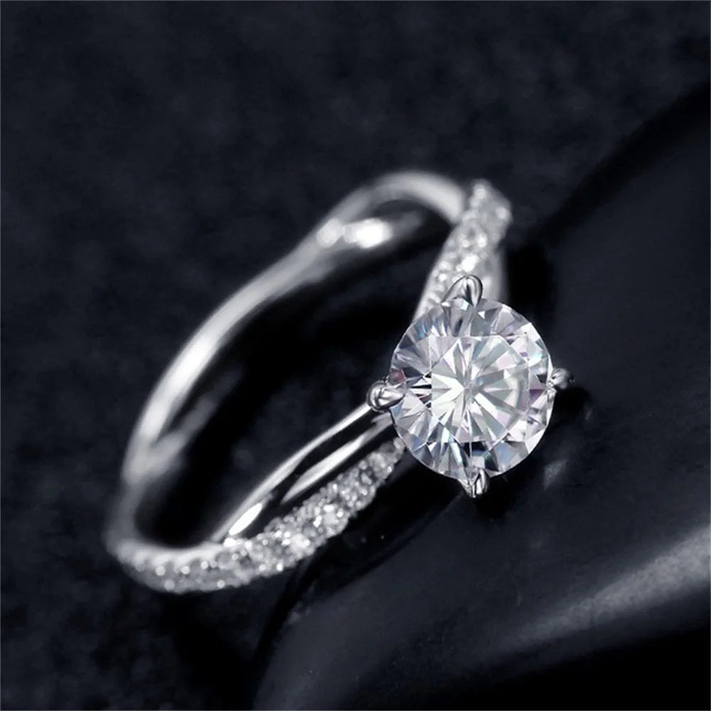 Primer plano de un anillo de compromiso CZ de corte princesa bicolor en un dedo contra un fondo oscuro.