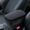 Close-up view of a black car armrest cushion with a red button on the side.