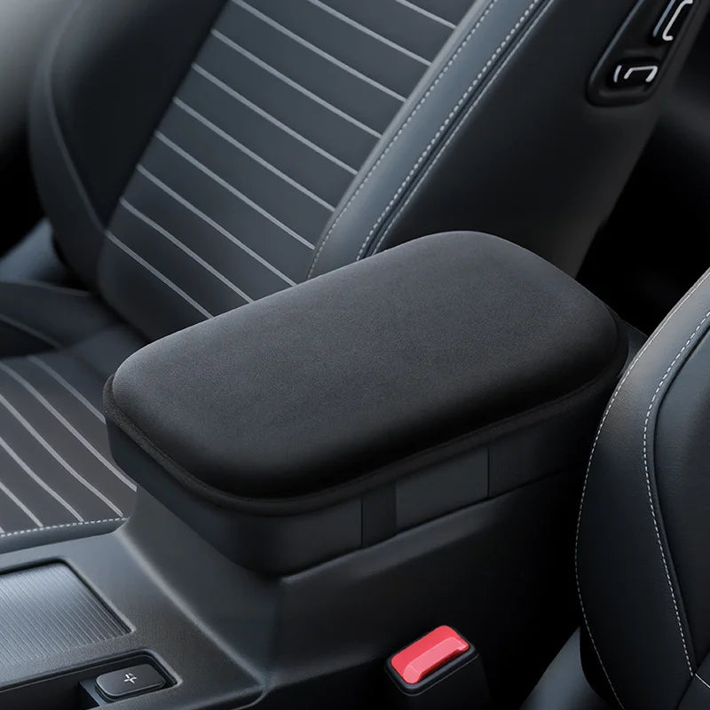 Close-up view of a black car armrest cushion with a red button on the side.