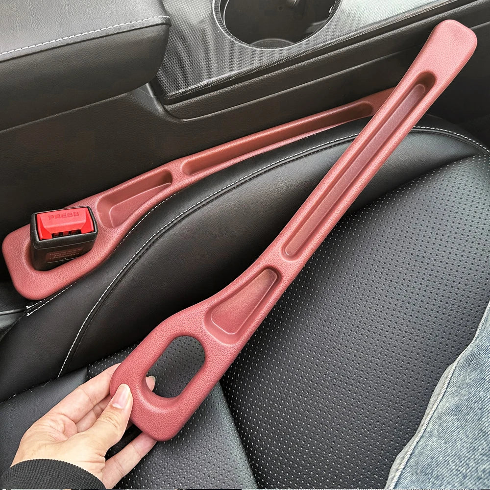 A hand holds a pink car seat gap filler and storage organizer designed for universal car seats.