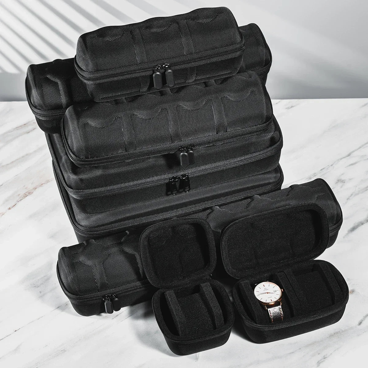 A stack of black portable leather watch travel cases with soft lining displayed on a white marble surface.