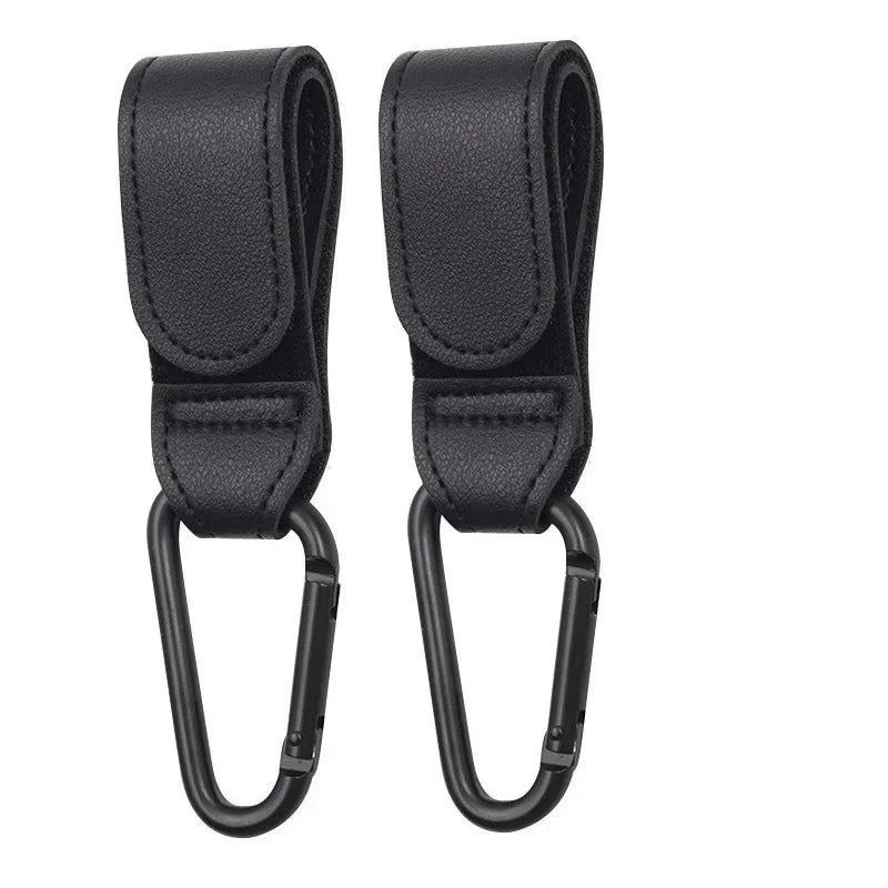 A pair of black PU leather stroller hooks with a rotating design for baby bag organization.