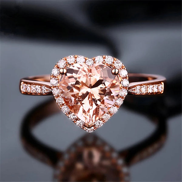 A close-up of a rose gold heart-shaped ring set with clear cubic zirconia stones.