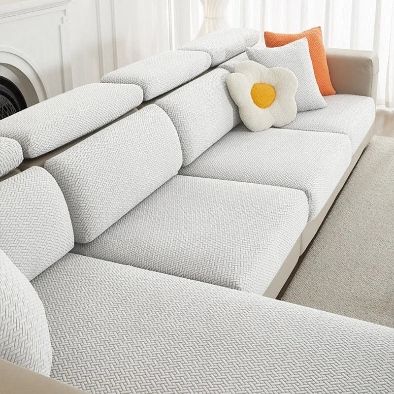 A modern white sofa with light gray cushions and orange accent pillows.