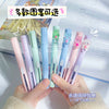 A hand holds several colorful folding pen-shaped safety scissors for craft and office.