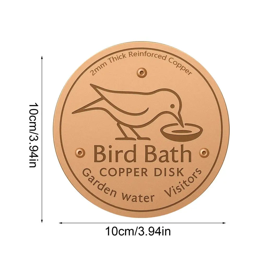 A round copper disk bird bath with a silhouette of a bird on it, designed for garden water.