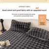 A dark gray quilted velvet blanket or pillow cover with a textured, fuzzy surface.