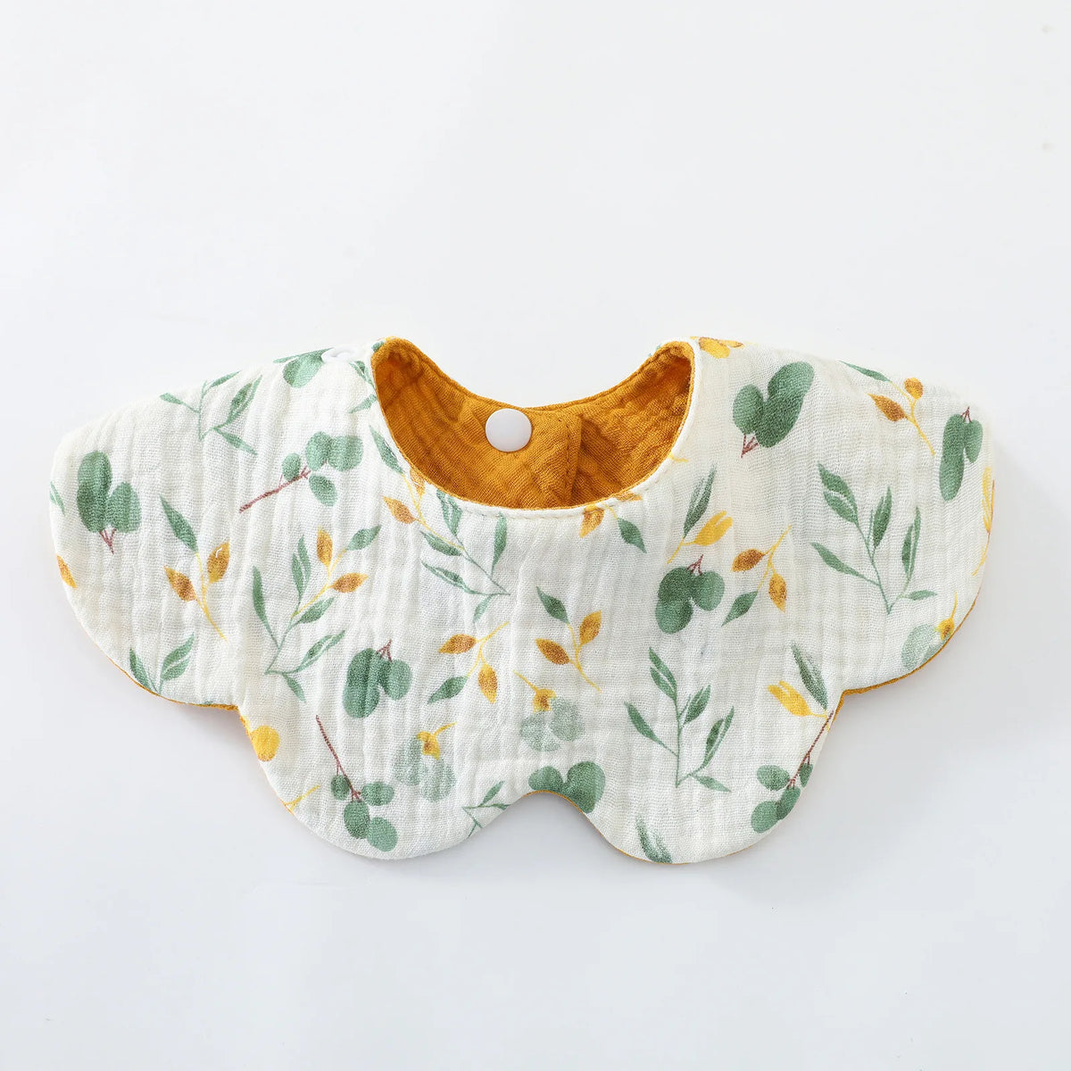 A white cotton baby feeding bib with a scalloped edge and embroidered green and yellow leaves, featuring a brown fabric backi