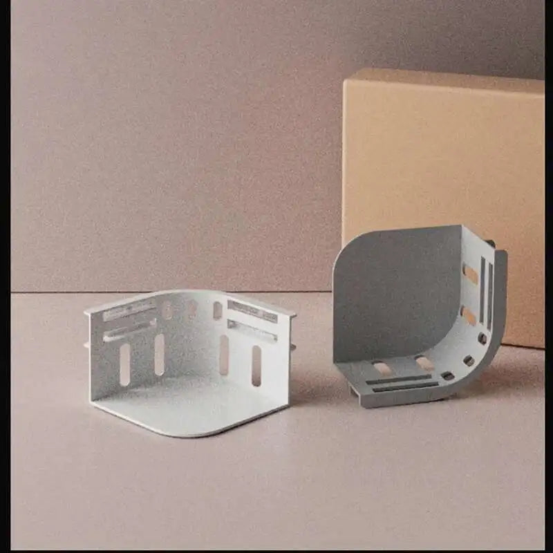 A light gray plastic bed sheet holder with multiple clips is shown next to a brown cardboard box.