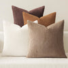A grouping of four textured throw pillows in shades of brown, beige, and cream corduroy fabric.