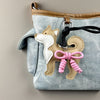 A light blue denim fabric bag featuring a tan Shiba Inu leather charm with a pink braided bow.