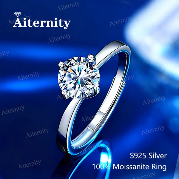 Anillo solitario con una piedra clara brillante en una banda de plata, mostrado sobre una superficie azul oscuro.