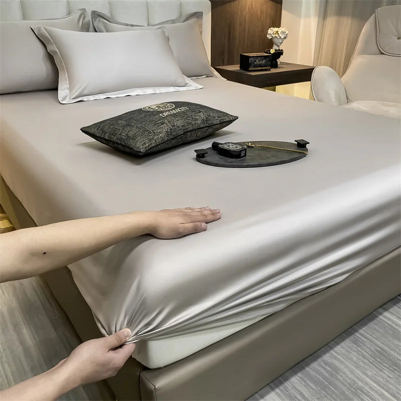 Un juego de sábanas ajustadas de algodón de lujo se muestra en una cama, con manos ajustando la tela.