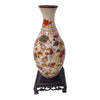 A ceramic vase with floral patterns and a reddish-brown rim displayed on a dark stand.