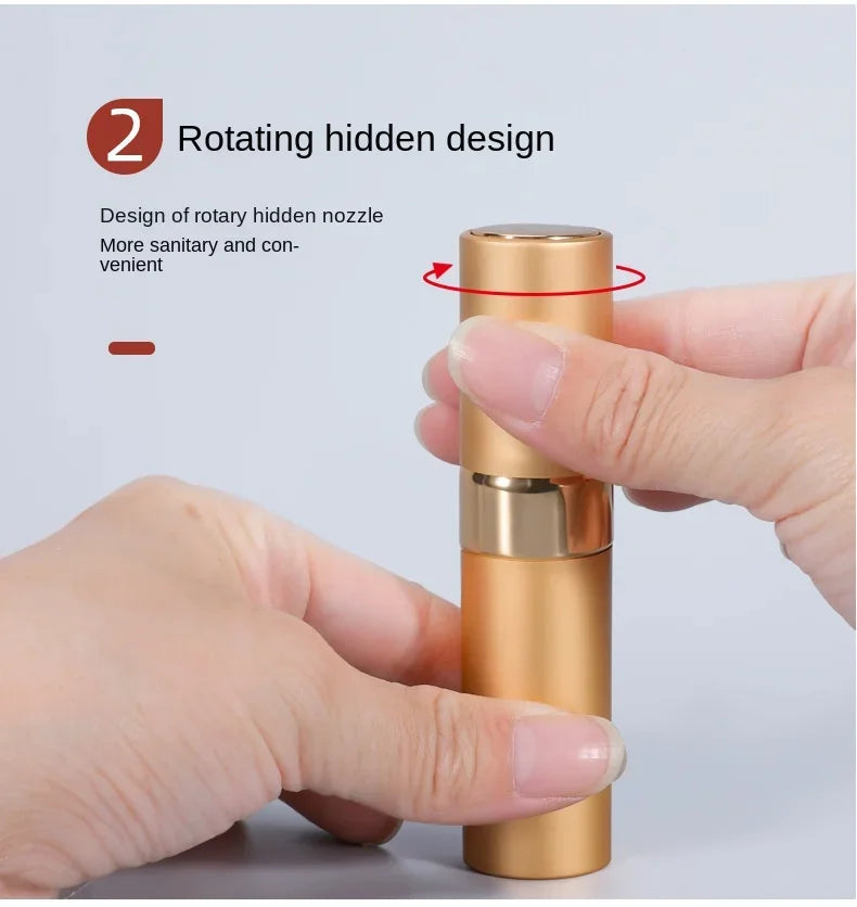 A hand is holding a gold-colored refillable perfume atomizer with a rotating hidden nozzle design.