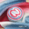 A roll of colorful gradient yarn showing pink, blue, and white swirls against a blue knitted fabric background.
