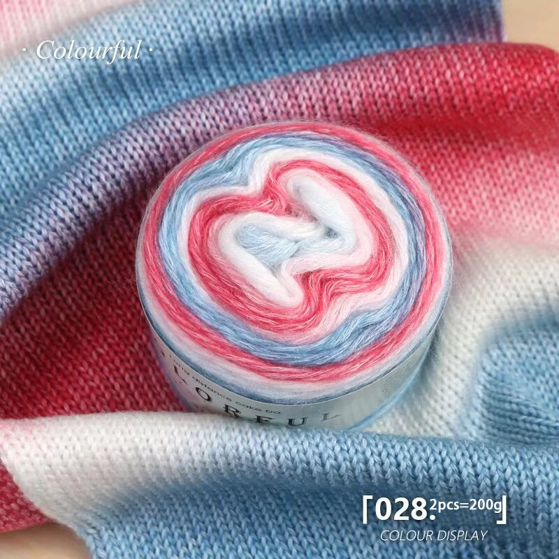 A roll of colorful gradient yarn showing pink, blue, and white swirls against a blue knitted fabric background.