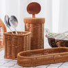 A collection of handwoven wicker serving baskets in various sizes and shapes, stacked on a white surface.
