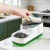 A hand is placing a sponge into the dispenser of a white countertop soap dispenser with a built-in sponge holder.
