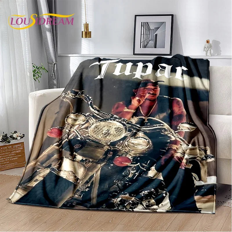 A dark graphic throw blanket featuring portraits of Eminem and Tupac in a vintage style.