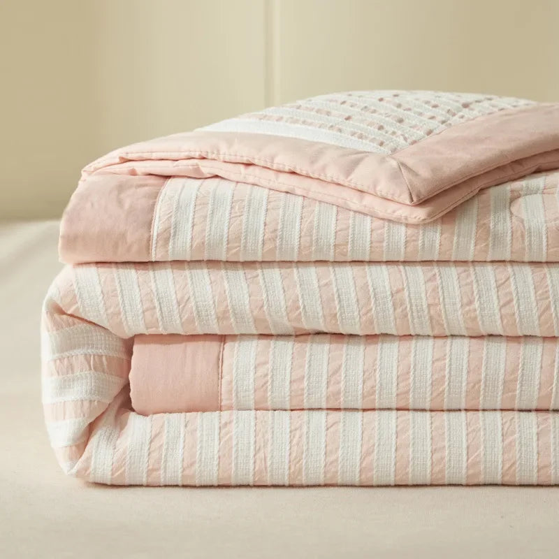 A stack of pink and white striped breathable summer quilts with jacquard cotton covers.