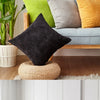 A set of striped velvet corduroy cushion covers in black, gray, lime green, and mustard yellow displayed on a wooden bench.