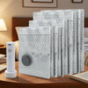 A stack of portable vacuum compression bags in light gray and white are displayed on a wooden table.