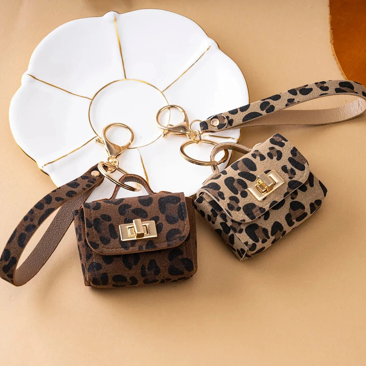 A leopard print PU leather keychain mini wallet with gold hardware resting on a white tile.