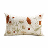 A cream-colored throw pillow cover featuring embroidered floral designs in shades of white, beige, and burnt orange.