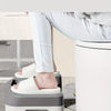 A person is using a white comfort squatting stool to solve sitting problems in a bathroom setting.