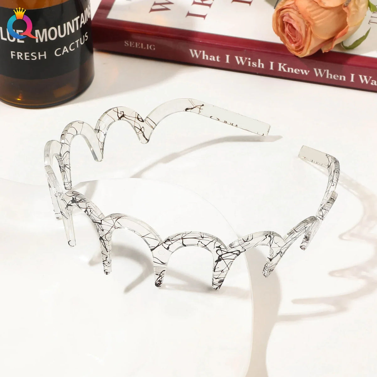 Clear acetate toothed hair band with a delicate vine pattern displayed on a white surface.