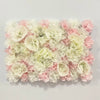 A dense wall panel of pink and white silk rose flowers for weddings and events.