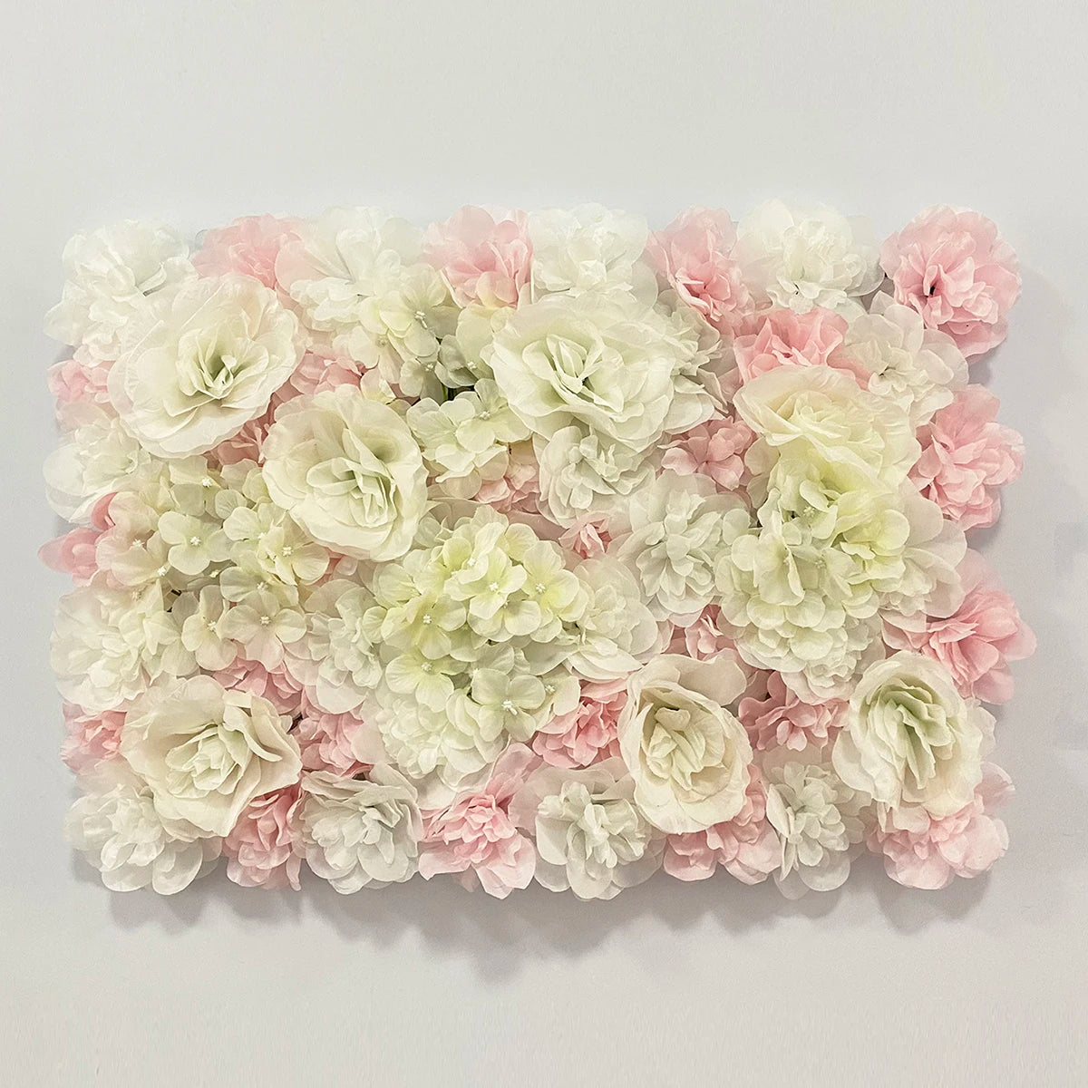 A dense wall panel of pink and white silk rose flowers for weddings and events.