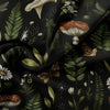 Dark fabric featuring a pattern of forest mushrooms, leaves, and small white flowers.