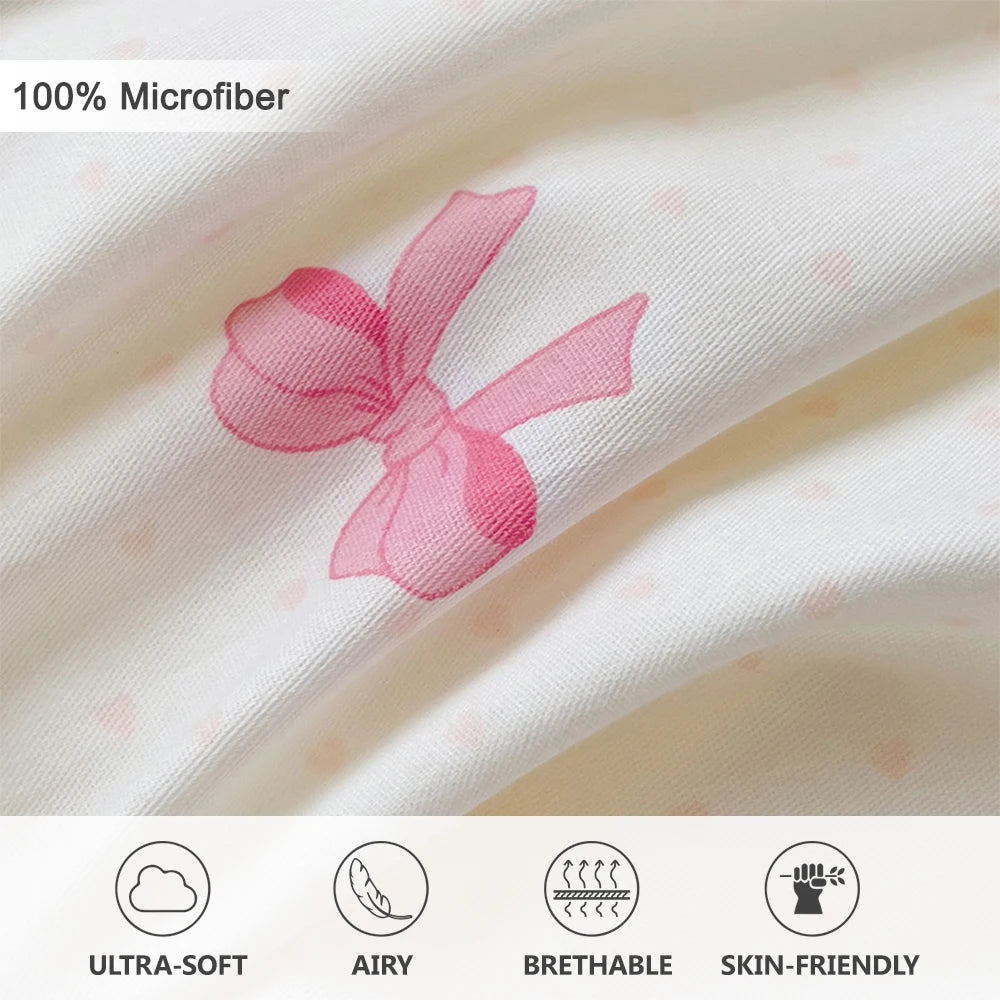 Close-up of a pink fabric with a printed bow design showing the texture and softness of microfiber bedding.