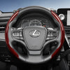A close-up view of a black steering wheel with red carbon fiber texture accents and controls.