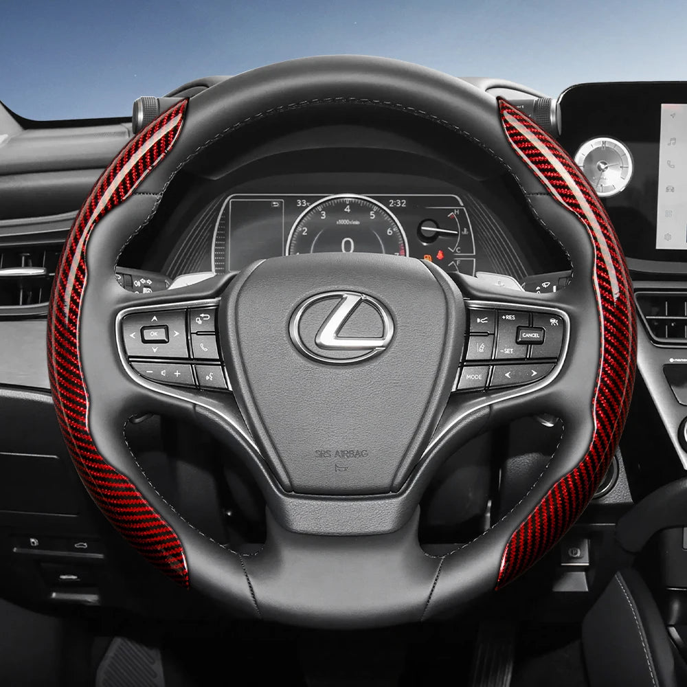 A close-up view of a black steering wheel with red carbon fiber texture accents and controls.