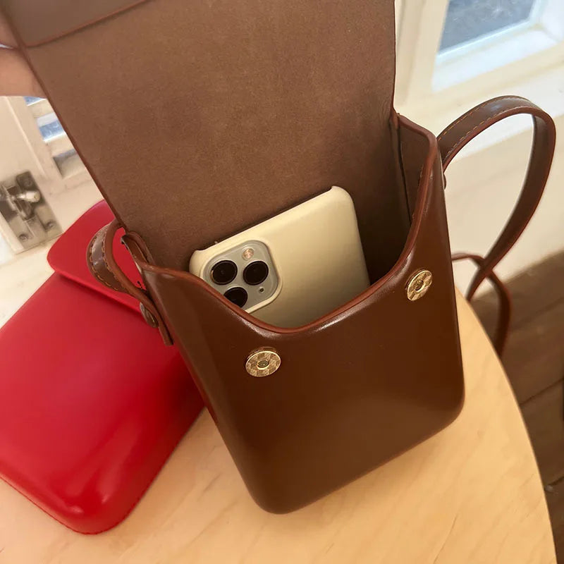 A brown vintage PU leather crossbody shoulder bag is shown open, displaying a light-colored smartphone inside.