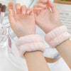 Two hands wearing soft pink microfiber wrist sweatbands and scrunchies for face washing