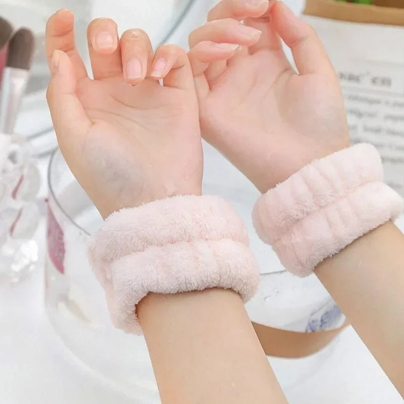 Two hands wearing soft pink microfiber wrist sweatbands and scrunchies for face washing