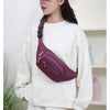 Une femme porte un sac à bandoulière en nylon rembourré violet sur son sweat blanc.