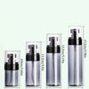 A set of clear glass refillable travel spray bottles with black pump tops and silver mist nozzles.