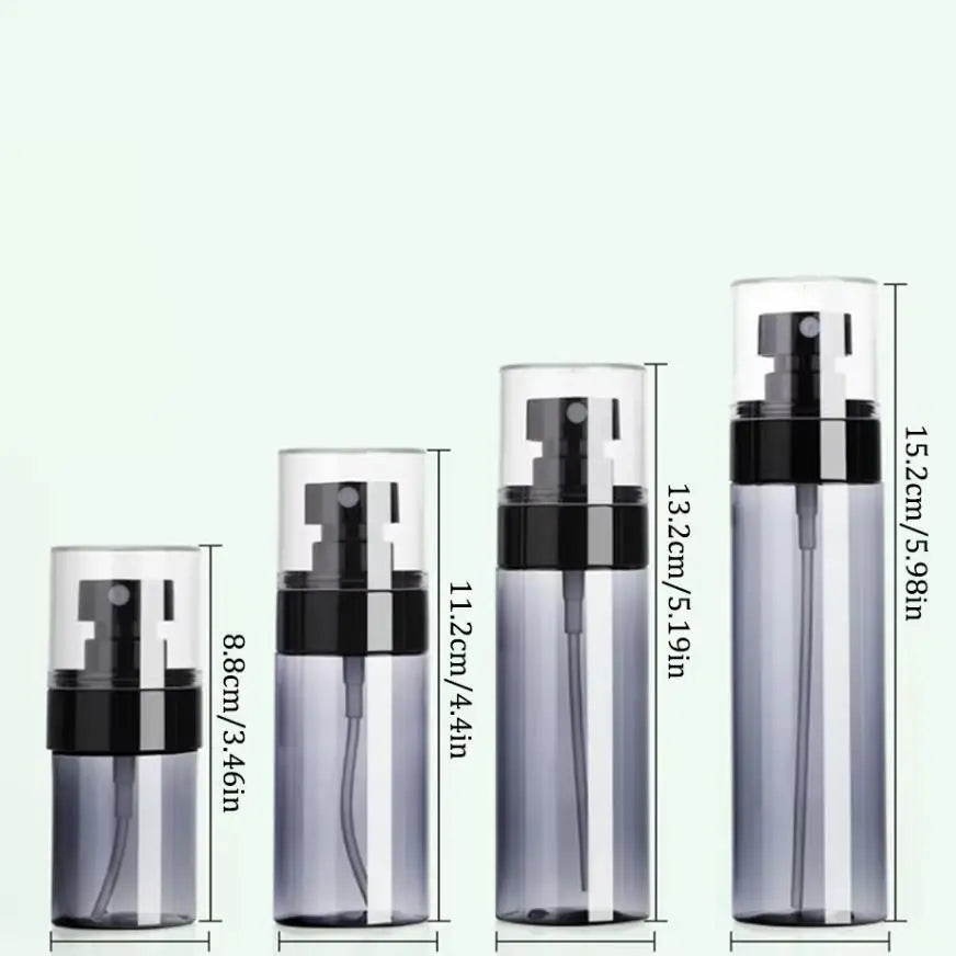 A set of clear glass refillable travel spray bottles with black pump tops and silver mist nozzles.