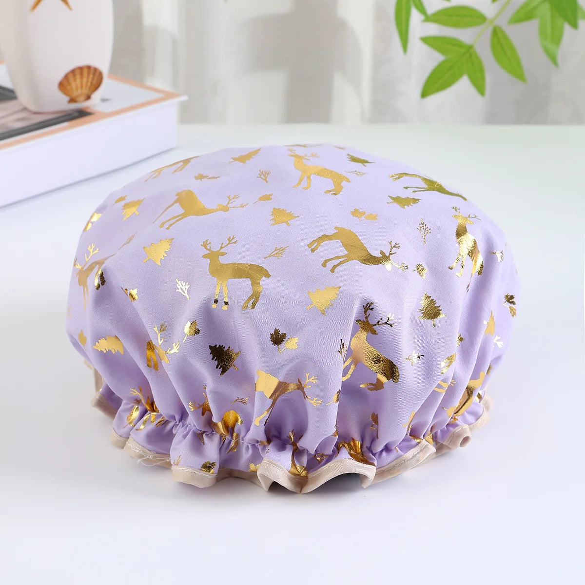 A purple reusable elastic shower cap decorated with gold deer and foliage patterns.