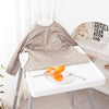 A beige long-sleeve waterproof baby bib with a cute animal design displayed on a white table.