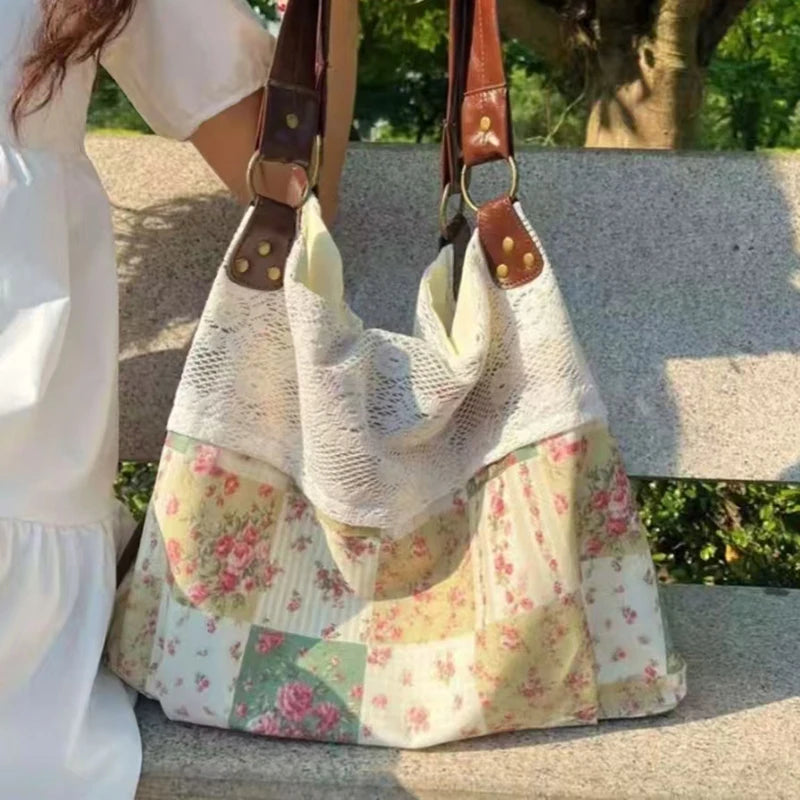 Un sac à main patchwork de couleur claire avec des motifs floraux est tenu par une personne dehors.