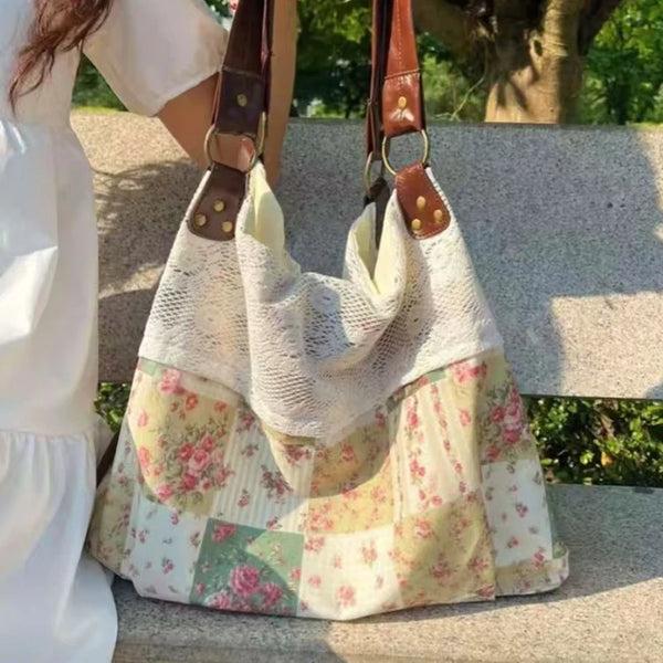 Un sac à main patchwork de couleur claire avec des motifs floraux est tenu par une personne dehors.