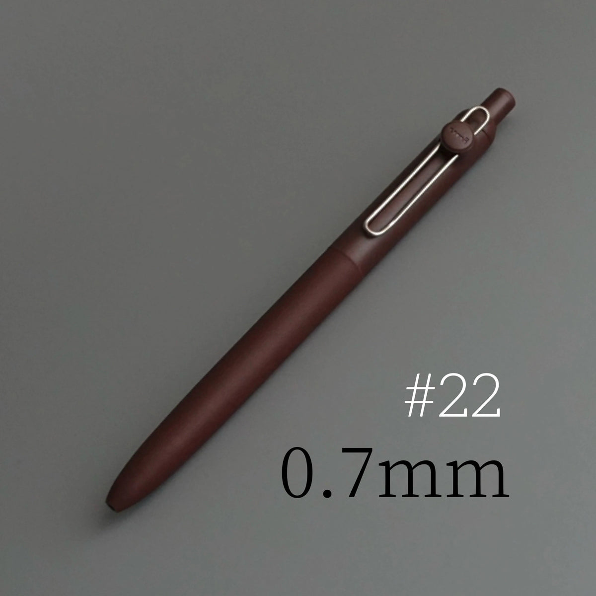 A brown Uni ZENTO quick-dry gel pen with a silver clip, shown diagonally on a gray background.