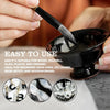 A hand is using a brush to apply black epoxy resin pigment onto a dark bowl for art purposes.