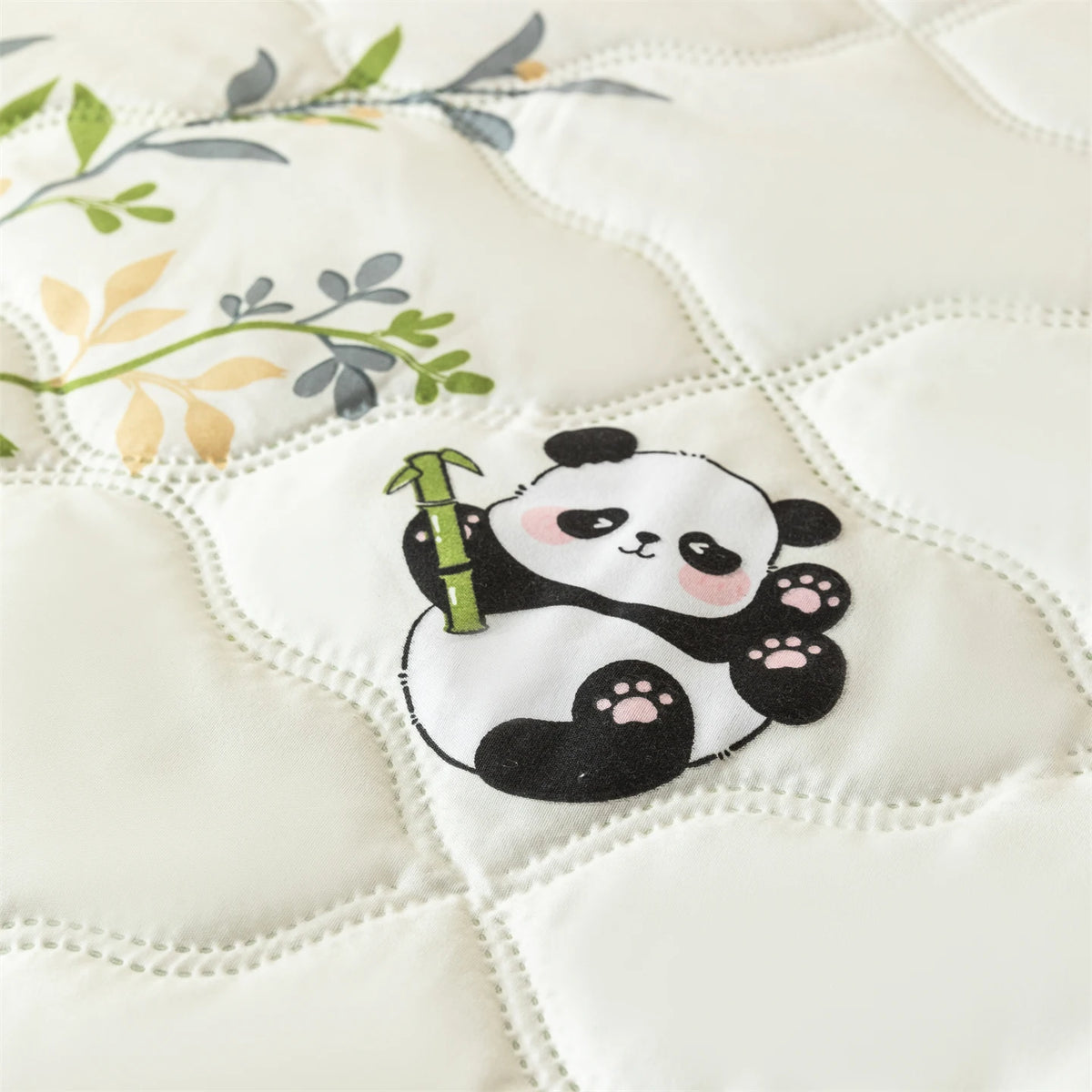 A white quilted fabric features a cute panda design with bamboo stalks and green leaves.